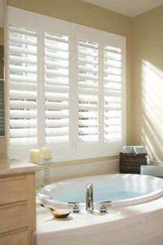 a bathroom with a large jacuzzi tub next to a window covered in blinds