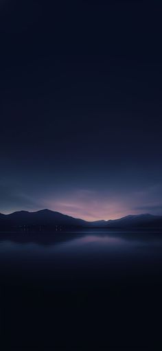 the sky is very dark and cloudy at night, with mountains in the far distance