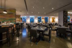 an empty restaurant with tables and chairs in front of colorful wall art on the walls