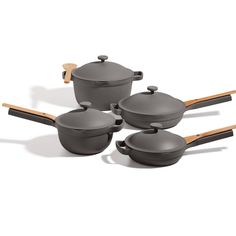 four pots and two pans with wooden spoons on the bottom one is gray