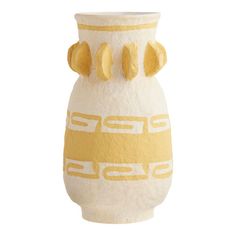 a yellow and white vase sitting on top of a table