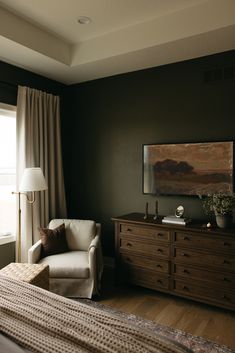 a bedroom with a bed, dresser and chair in front of a large painting on the wall