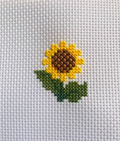 a cross stitch sunflower with green leaves