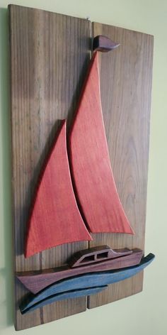 a wooden sailboat mounted to the side of a wood plank wall hanging on a wall