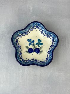 a small blue and white bowl with flowers on the inside, sitting on a gray surface