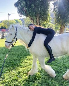 a woman riding on the back of a white horse