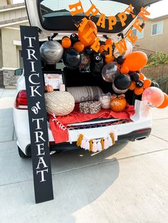 the trunk of a car is decorated with orange and black balloons, letters, and decorations