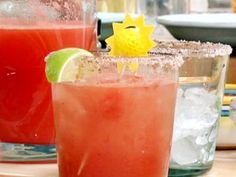 two glasses filled with watermelon and limeade sitting on a table next to each other