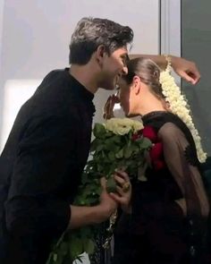 a man and woman kissing each other in front of a mirror with flowers on it