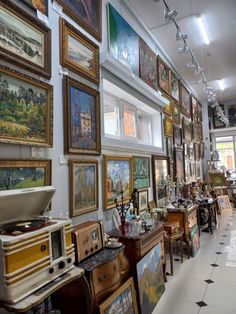 a room filled with lots of framed pictures on the wall next to tables and chairs