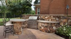 an outdoor kitchen with stone walls and grill