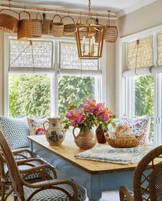 a dining room table and chairs with flowers in vases on the table next to them