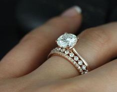 a woman's hand with a diamond ring on top of her finger and the other hand holding an engagement ring