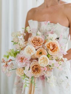 a woman holding a bouquet of flowers in her hand and wearing a dress with floral print on it