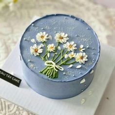 there is a blue cake with flowers on the top and white daisies in the middle