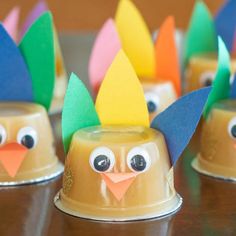 some paper turkey cups are sitting on a table with their faces painted to look like they're wearing thanksgiving hats