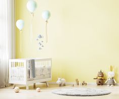 a baby's room with yellow walls, white crib and toys on the floor