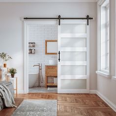 a bedroom with white brick walls and wooden flooring, an open door leading to the bathroom