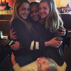 three girls hugging each other in a living room