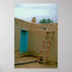 a ladder leaning up against a wall next to a blue door and adobe - style building