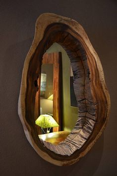 a mirror that is on the side of a wall next to a table with a lamp