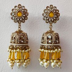 Embrace the allure of tradition with our Yellow Crystal and Pearl Suspended Kundan Jhumka Set--a premium ensemble of exquisite Indian craftsmanship. These Bollywood-inspired earrings effortlessly blend Pakistani elegance with a touch of regality. Adorned with radiant yellow crystals and delicate pearls, the intricate Kundan work lends a timeless charm to this jhumka set. Elevate your style and make a statement with these resplendent earrings that capture the essence of cultural opulence. Materials: Metal Alloy, Crystal, Pearl, Kundan ❋❋ Shipping Methods ❋❋ Standard Delivery - Take up to 8-14 business days (Worldwide). ❋❋ Please be aware that the colors, shades, and texture shown may exhibit minor variations compared to the actual product due to limitations in digital imaging. We kindly ask Yellow Jhumka Earrings, Cutdana Dangle Jhumkas For Festivals, Diwali Celebration Dangle Jhumkas, Cutdana Jhumkas For Celebration, Celebration Cutdana Drop Jhumkas, Festival Celebration Jhumkas Drop Earrings, Heavy Dangle Jhumkas For Diwali, Traditional Jhumkas With Matching Earrings For Eid, Heavy Drop Jhumkas For Diwali