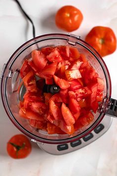 a blender filled with sliced tomatoes on top of a counter