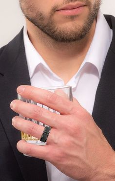 a man wearing a black suit and white shirt holding a ring