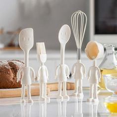 small white kitchen utensils lined up in front of bread on a cutting board