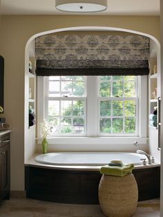 a bath tub sitting under a window next to a sink and stove in a bathroom