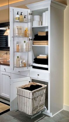 a bathroom with white cabinets and shelves filled with personal care items, including a laundry basket