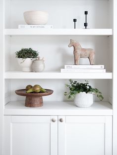 a white bookcase filled with books and vases on top of eachother