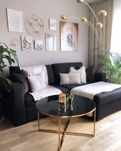 a living room with black couches, white pillows and gold accents on the walls