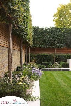 an outdoor garden with grass, shrubs and trees in the back yard area is well manicured