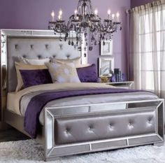 a purple and silver bedroom with chandelier above the bed