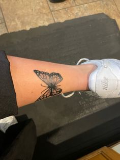 a woman's arm with a butterfly tattoo on the left side of her leg