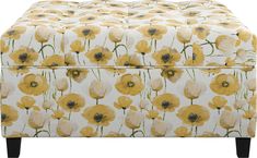 a yellow and white ottoman with flowers on it's back side, sitting in front of a white background