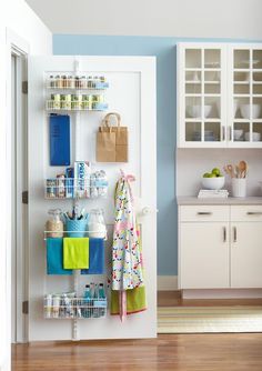 a kitchen with blue walls, white cabinets and shelves filled with various items on the wall