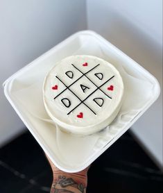 a hand holding a cake with the word dad written on it in black and white