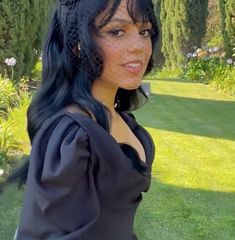 a woman in a black dress and veil posing for the camera with her hands on her hips