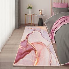 a bed with pink and grey comforter next to a white rug on the floor