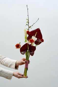 a woman holding a bouquet of flowers in her hand with the sky in the background