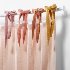 four different colored ties hanging on a curtain rod