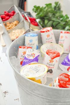 an assortment of frozen yogurts in buckets on a table with other food items