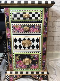 a multicolored dresser with black and white checkered drawers, gold knobs and flowers