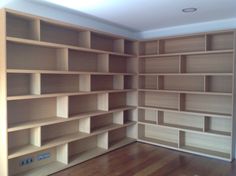 an empty room with wooden shelves and hard wood flooring