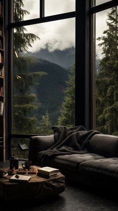 a living room filled with furniture and a large window overlooking the mountain range in the distance