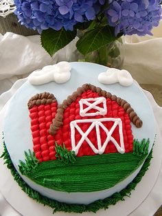 a cake decorated to look like a farm scene with blue hydranges in the background