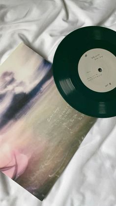 a record sitting on top of a bed next to a white sheet with an image of a woman's face