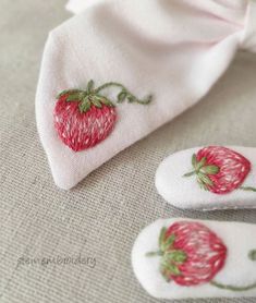 two pairs of white socks with red strawberries on them and one pair of pink slippers